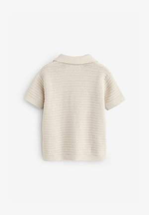 Kötött krémszínű pólóing rövid ujjakkal, texturált, vízszintes csíkokkal és puha gallérral. Könnyű, lélegző anyag.