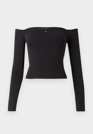 Mustast pikast varrukast lahti õlavarre pealt top, mis on valmistatud venivast kangast, koos keha järgiva disaini ja kõveraga hemline'iga. Omab väikest logo aktsenti.