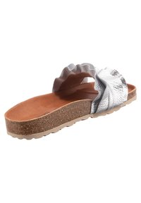 Zilveren sandaal met een gerimpeld ontwerp, kurken zool en tan binnenzool. Het bovendeel heeft een gestructureerd metallic materiaal en zachte grijze accenten.