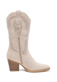 Bota western de ante beige con punta afilada, costuras decorativas, diseño perforado, cremallera lateral y tacón de madera apilada.