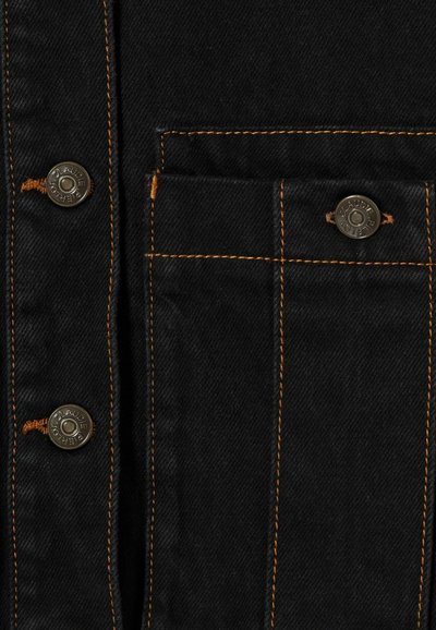 Tessuto denim nero con cuciture arancioni, caratterizzato da bottoni automatici metallici e una patta della tasca fissata da un bottone.