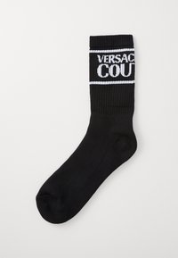 Juodas megztas kojinės su raukšlėtu viršumi, su balta "VERSACE COURT" užrašu, apsuptu baltos juostos. Lygi tekstūra, vidutinio ilgio iki blauzdos.