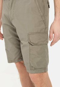 Lichte cargoshorts van olijfgroen materiaal. Beschikt over zijzakken met kleppen, een elastische tailleband en gestikte afwerkingsdetails.