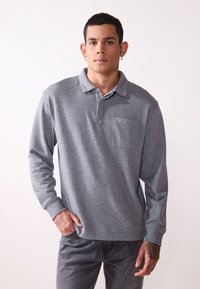 Polo grigio a maniche lunghe con colletto, taschino sul petto e orlo dritto. Tessuto morbido con una leggera trama e design aderente.