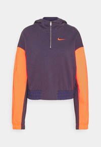 Krátká mikina s kapucí v tmavě modré a výrazné oranžové barvě. Má přední poloviční zip, elastický lem a malé logo Nike na hrudi. Jemná látka.