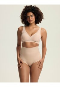 Beżowy bezprzewodowy stanik o gładkiej fakturze i dekolcie w kształcie V, w połączeniu z bielizną o wysokim stanie w tym samym kolorze, charakteryzującą się bezszwowym wyglądem.