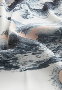 Stof met abstracte penseelstreekpatronen in zwart en lichtroze op een witte achtergrond, met zachte plooien en textuurdetails.