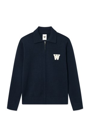 Cardigan zippé en maille bleu marine avec col plat, poignets et ourlet côtelés, arborant un logo "W" stylisé blanc sur la poitrine gauche.