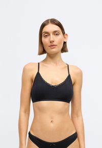 Μαύρο βαμβακερό bralette με λεπτή δαντέλα στο τελείωμα, διαθέτει λαιμόκοψη με κυματιστό τελείωμα, υφή με μοτίβο και ρυθμιζόμενους ιμάντες για τέλεια εφαρμογή.