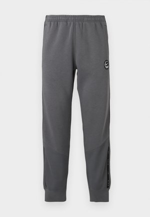 Gray sweatpants made of soft fabric with an elastic waistband, tapered legs, side panels, and a circular logo patch.