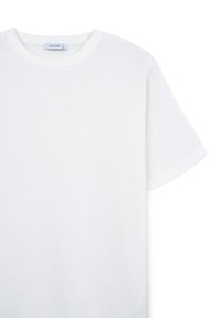 T-shirt bianco a maniche corte realizzato in un tessuto testurizzato. Design con collo rotondo e un sottile motivo a maglia con vestibilità rilassata.