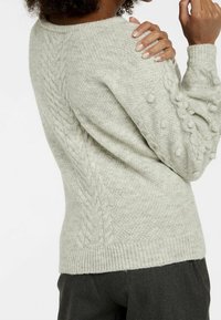 Hellgrauer Pullover mit strukturiertem Strickmuster, das Zopfmuster und Noppenakzente an den Ärmeln aufweist. Gerippte Bündchen und Saum sorgen für eine enganliegende Passform.