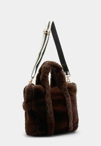 Brun faux fur håndtaske med to top-håndtag og en aftagelig stribet skulderrem. Har guldhardware og en blød, struktureret overflade.
