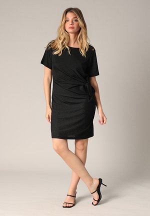 Robe noire à manches courtes en tissu scintillant, avec un accent noué à la taille, et une coupe droite se terminant au-dessus du genou.