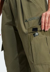 Terrex cargo hlače u maslinastoj boji, s opuštenim krojem, teksturiranim materijalom, bočnim džepovima s či�čak zatvaranjem i detaljem s ušivenim logotipom.