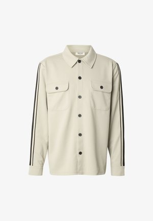 Helebeežist beež triiksärk kraega, ees nupud, kaks rinnataskut ja mustad triibud varrukate külgedel. Sile tekstuur, vabaaja disain.