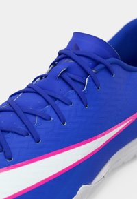 Παπούτσι με υφασμάτινη μπλε συνθετική επένδυση, ροζ και λευκές λεπτομέρειες, και μπλε κορδόνια. Κοντινή λήψη της περιοχής του δακτύλου και του συστήματος δέσιμο.