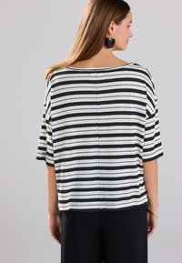 Striped short-sleeve top featuring black and white horizontal stripes, relaxed fit, wide neckline, and soft textured fabric.