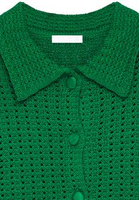 Groene gebreide cardigan met een textuurpatroon, een kraag en knoopsluitingen. Het materiaal is licht en ademend.
