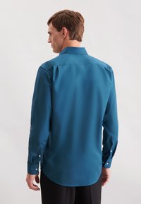 Teal button-up shirt met een achterkant yoke ontwerp, lange mouwen en knopen op de manchetten. Glad textuur, de uiteinden zijn afgerond. Geschikt voor formele settings.