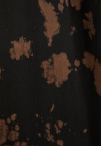 Black fabric with a textured surface featuring irregular brown bleach stains, creating a contrasting pattern throughout.