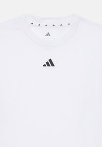 Biała koszulka z okrągłym dekoltem, wykonana z bawełny, z małym czarnym logo adidas na piersi oraz czarnymi detalami wewnątrz kołnierzyka.