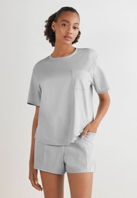 Grijze katoenen T-shirt met een ronde hals en korte mouwen, voorzien van een linker borstzak, gecombineerd met bijpassende grijze shorts.