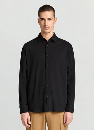 Chemise noire à manches longues avec un devant boutonné, un col et un tissu texturé. Elle présente des poignets standards et une coupe décontractée.