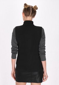 Vest negru din fleece cu guler înalt, mâneci lungi gri și o textură fină. Prezintă un design ajustat cu un tiv ușor evazat.