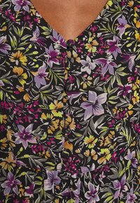 Robe imprimée florale noire, présentant des fleurs vibrantes violettes, jaunes et vertes. Détails remarquables : un décolleté en V et des boutons en guise d'accent.
