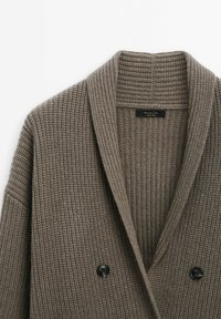 Cardigan en maille double boutonnage taupe avec col châle et boutons noirs, tissu en laine texturé, étiquette Massimo Dutti à l’intérieur du col.
