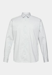 Chemise blanche à manches longues avec boutons, col pointu et poignets boutonnés, présentée sur un fond uni gris clair.