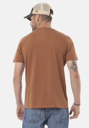 T-shirt en coton brun avec un col rond et des manches courtes, présentant une texture lisse. La vue arrière montre un design simple et sans graphismes.