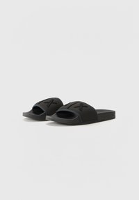 Infradito nere con apertura sulla punta, dotate di una parte superiore testurizzata, design a fasce incrociate e suola piatta per il massimo comfort.