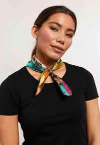 Silk scarf featuring a vibrant pattern with turquoise, orange, pink, and black accents, tied around the neck with pointed ends.