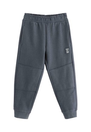Pantaloni della tuta per bambini grigio scuro con vita elastica, tasche laterali, polsini a coste, toppe imbottite sulle ginocchia e patch "GIOCA TUTTO IL GIORNO" sulla coscia.