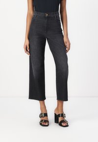 Μαύρα τζιν παντελόνια με ψηλή μέση και φαρδιά μπατζάκια, αντιθετική ραφή, πλαϊνές τσέπες και χρυσό κουμπί κλεισίματος στη μέση.