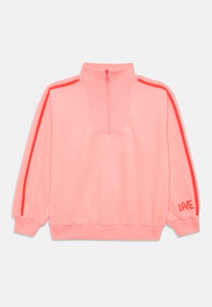 Pull en polaire rose avec zip partiel, rayures rouges le long des manches, poignets et ourlet côtelés, et texte rouge "LOVE" sur le poignet gauche.