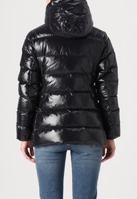 Schwarze, glänzende Steppjacke mit Kapuze, mit gestepptem Design und vertikalen Streifen. Die Rückansicht zeigt isolierte Einsätze und eine lockere Passform.