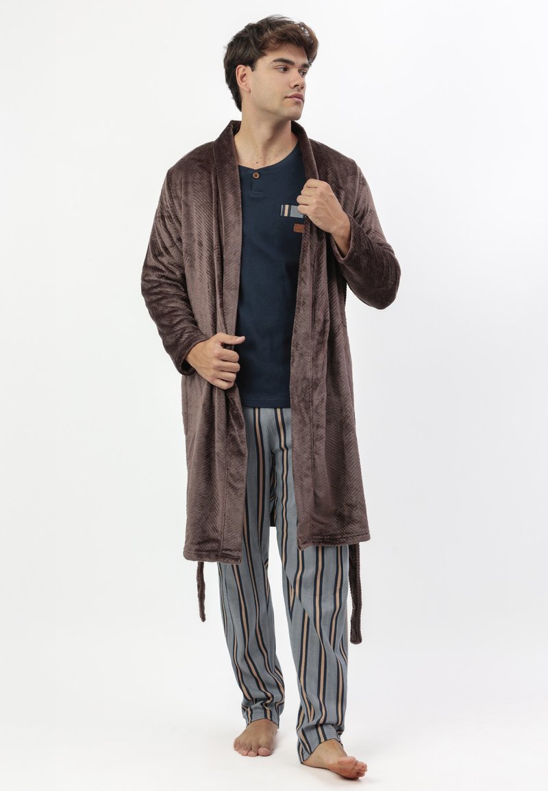 Bata de felpa marrón con un patrón texturizado, combinada con pantalones de pijama a rayas en tonos de azul, gris y crema, con una camiseta azul abotonada.