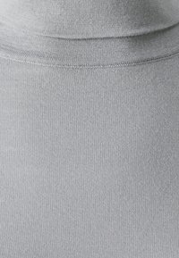 Pull à col roulé gris en maille côtelée, avec un col montant et un design sans couture, offrant une texture lisse.
