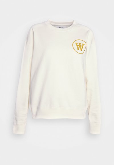 Sweatshirt crem cu mâneci lungi, gât rotund și un logo circulat galben pe pieptul stâng. Fabricat dintr-un material moale.