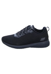 Scarpa sportiva nera con tomaia texture, design a coste e punta rotonda. Lacci piatti e suola imbottita. Logo del marchio sul lato.