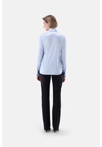 Light blue long-sleeve shirt with a collar, featuring buttoned cuffs, paired with black tailored trousers and sleek black shoes.