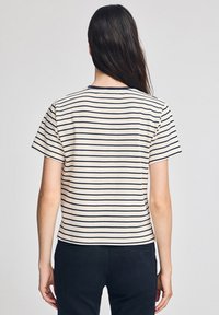 Randig t-shirt i krämfärgad och marinblå färg, korta ärmar, rund halsringning, mjukt bomullstyg, med horisontella ränder och en avslappnad passform.