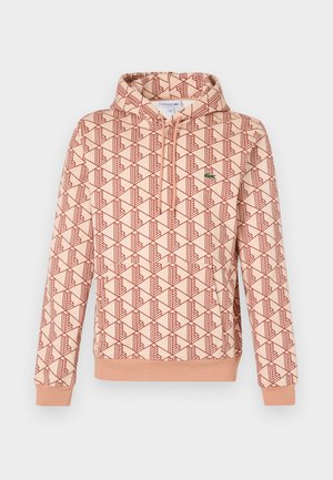 Sudadera con capucha en melocotón claro con un patrón geométrico rojo. Tiene un cierre frontal y puños acanalados. Logo pequeño en el pecho.