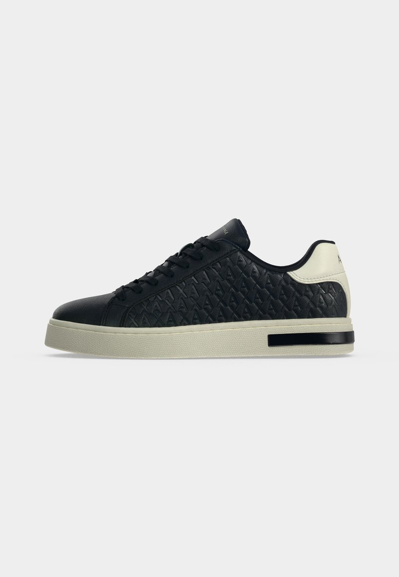 Μαύρο χαμηλό sneaker με υφασματικό μοτίβο στο πλάι, μαύρα κορδόνια και λευκή σόλα και περιλαμβάνει φτέρνα με μαύρη ρίγα στη σόλα.