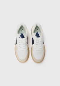 Hvide sneakers med marineblå accenter, perforeret tåboks og beige gummisål. Tekstureret stof på siden og tungen med synligt brandlogo.