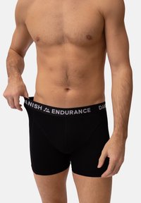 Zwarte boxershorts met een grijze elastische tailleband waarop de tekst "DANISH ENDURANCE" staat. De stof lijkt glad en aansluitend met minimale naden.