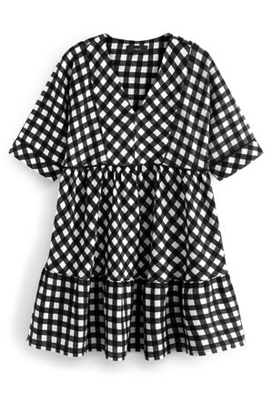 Robe courte à manches courtes à carreaux noirs et blancs avec col en V et panneaux superposés sur la jupe, dans un style ample et décontracté.